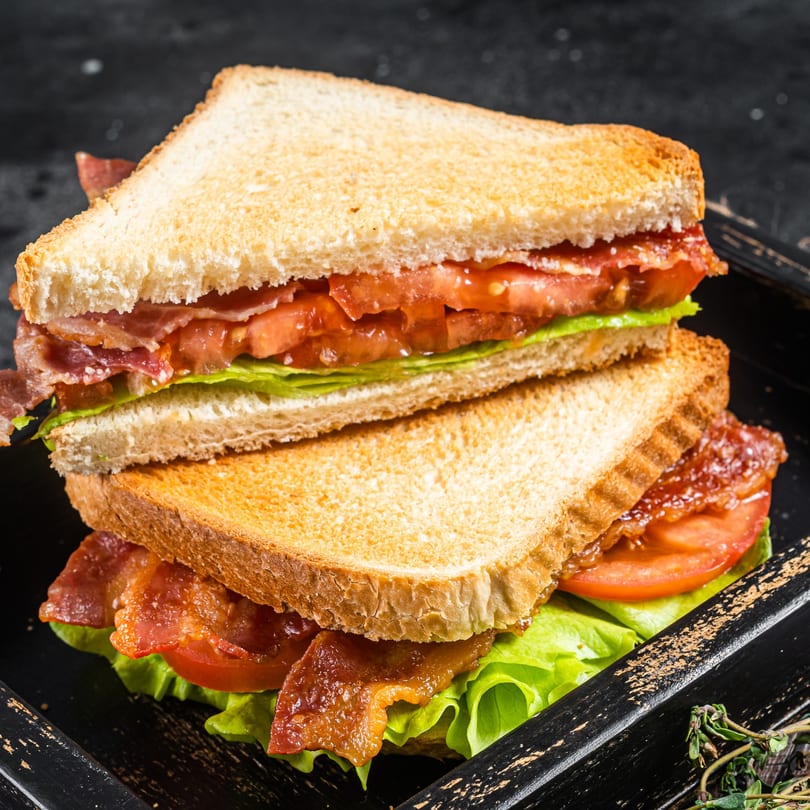 A stacked BLT sandwich with crispy bacon, fresh lettuce, and sliced tomatoes on toasted bread.